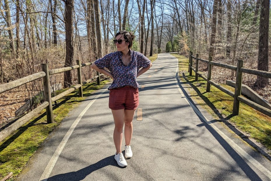 Amy full body on a bike path in home made shorts and second hand button down shirt